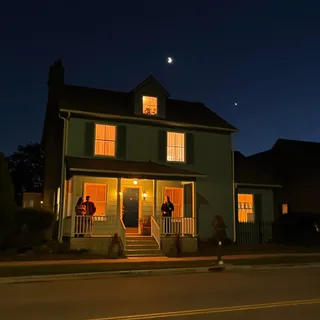 A house at night with lit windows and a moon