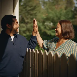 Two neighbors giving a high-five over a fence
