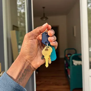 A hand holding house keys at an open front door