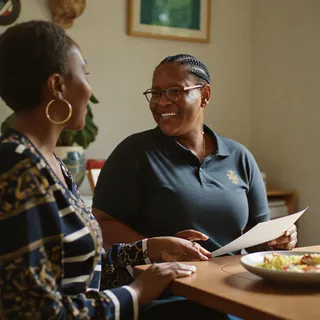Two people talking at a table with a paper